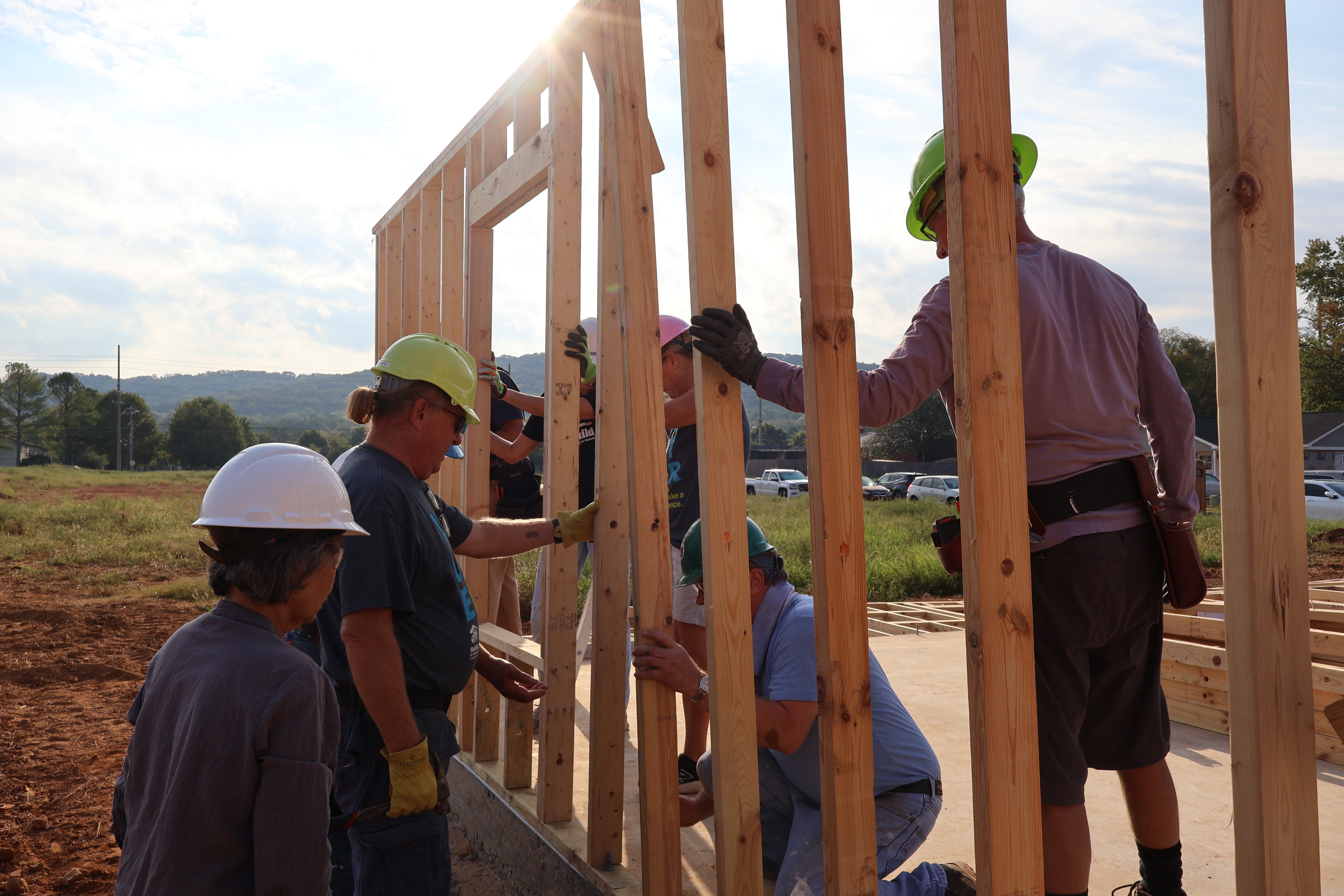Volunteers framing the walls of a new Habitat home at sunset