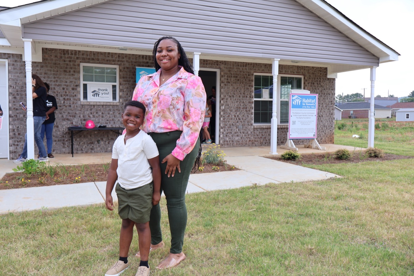 A Habitat homeowner and her son in front of their new home