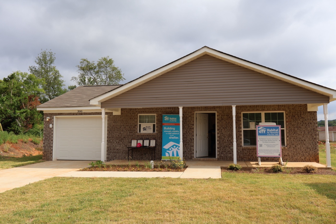 A completed Habitat home with families gathered at the dedication ceremony