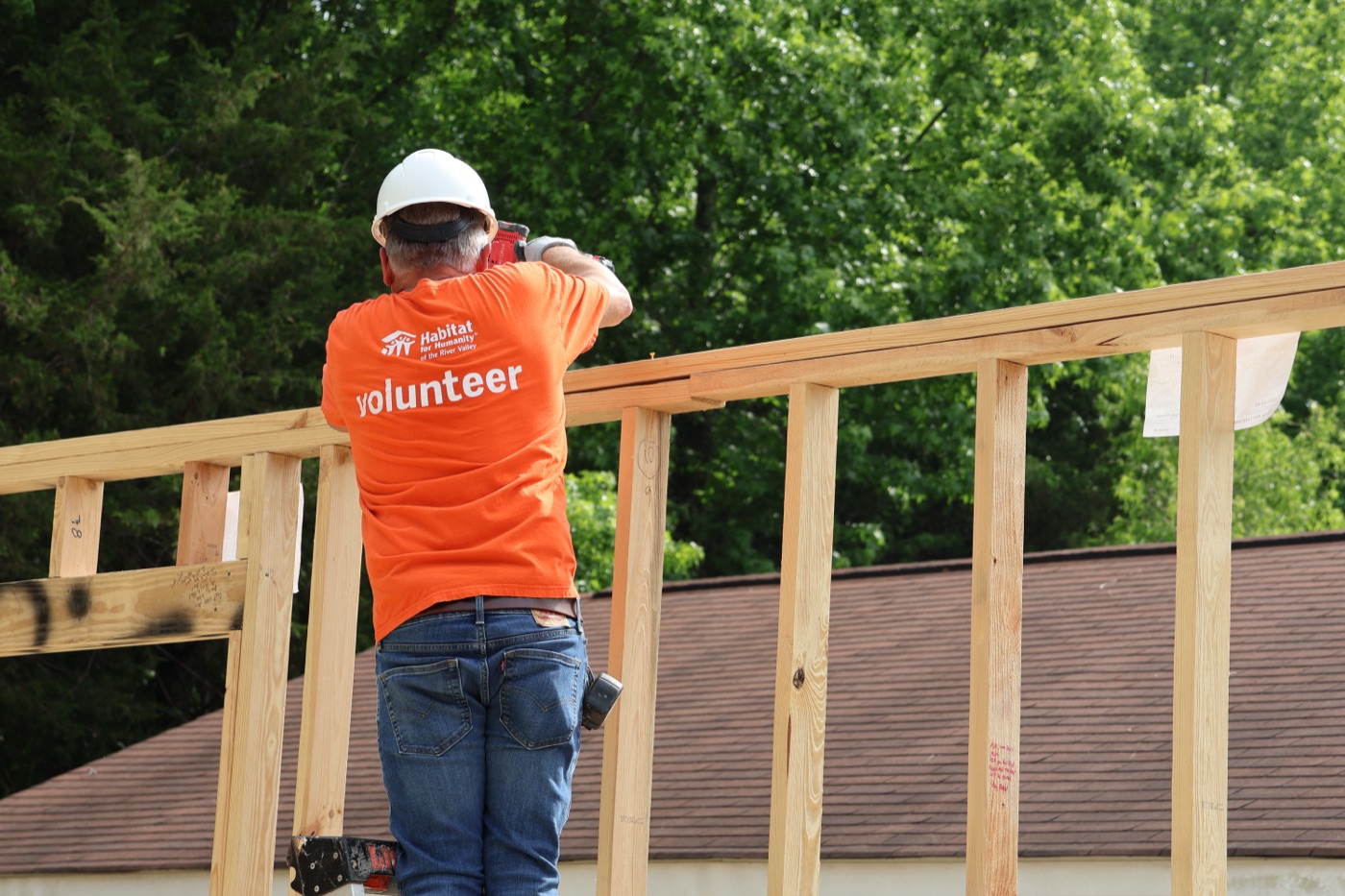 Smiling Habitat volunteers carrying lumber in the workshop